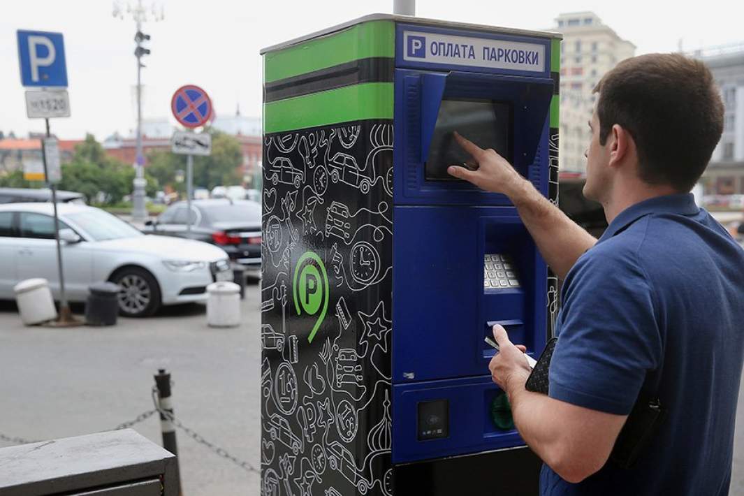 Житель города у паркомата на платной парковке