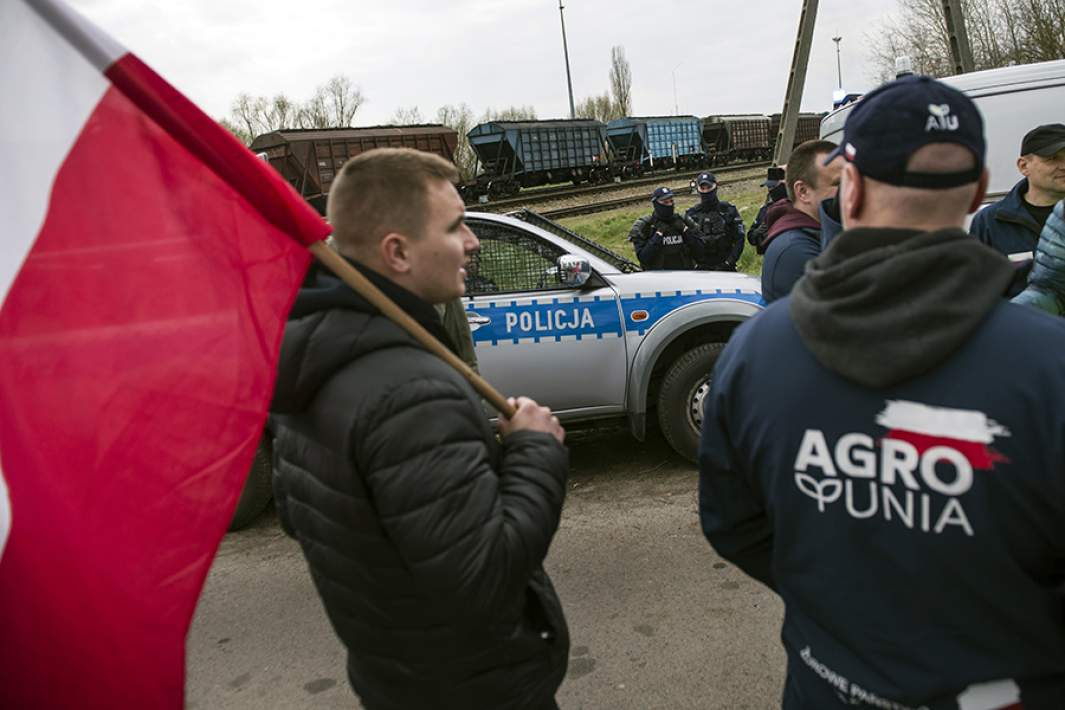 Сотрудники полиции и протестующие фермеры и проезжающего мимо поезда с украинским зерном в городе Грубешув, Польша