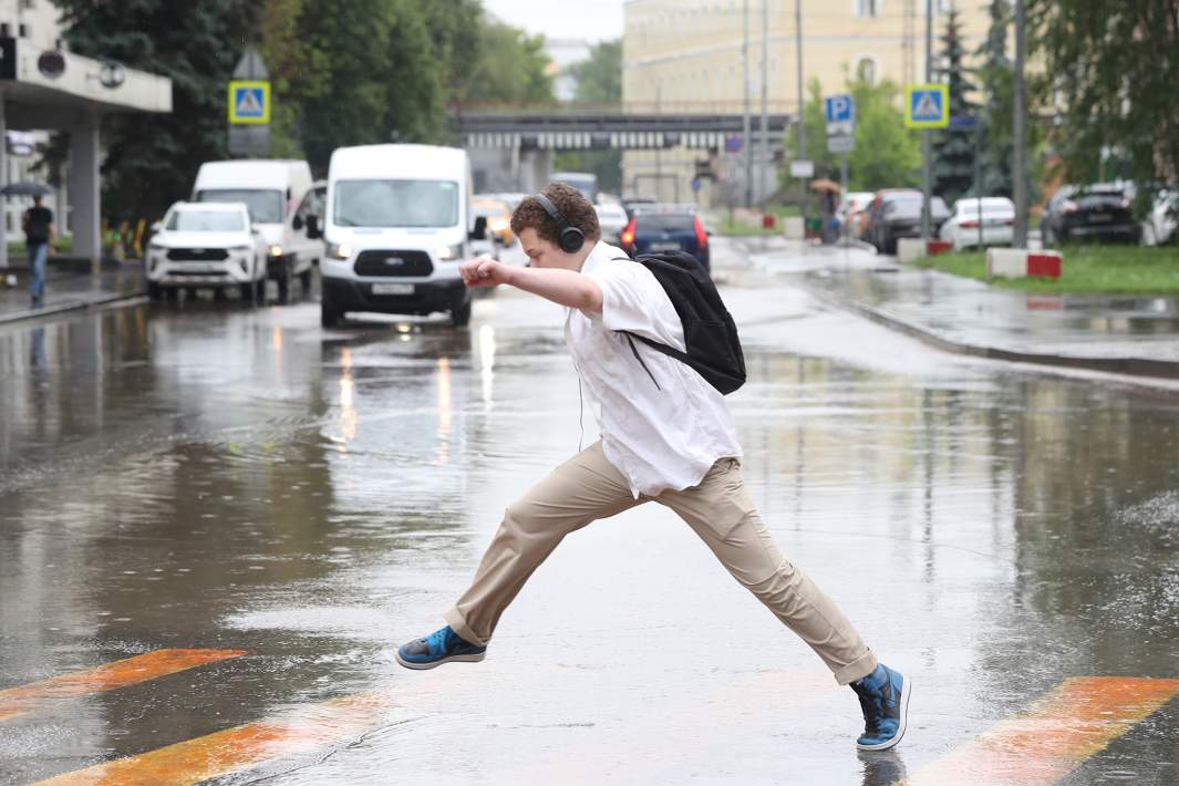 Молодой человек перепрыгивает лужу