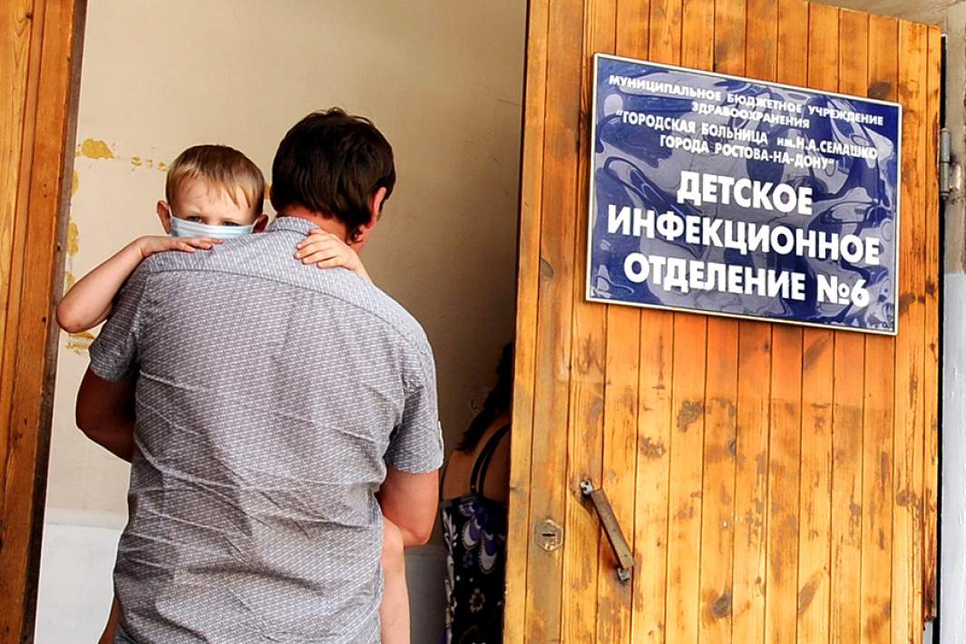 Родители с ребенком у входа в детское инфекционное отделение